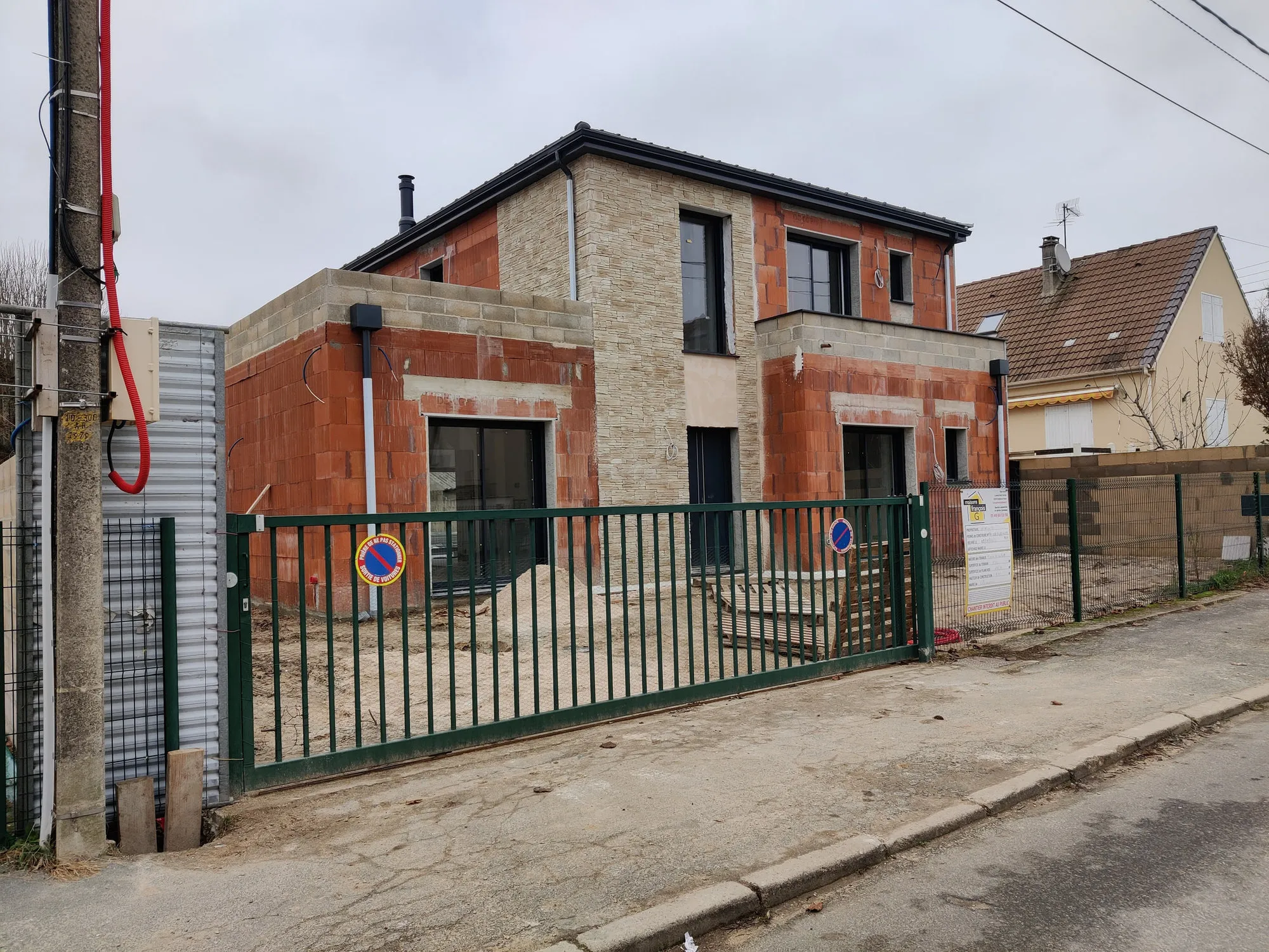 Façade sur rue en cours de chantier, maçonnerie brute et menuiseries posées