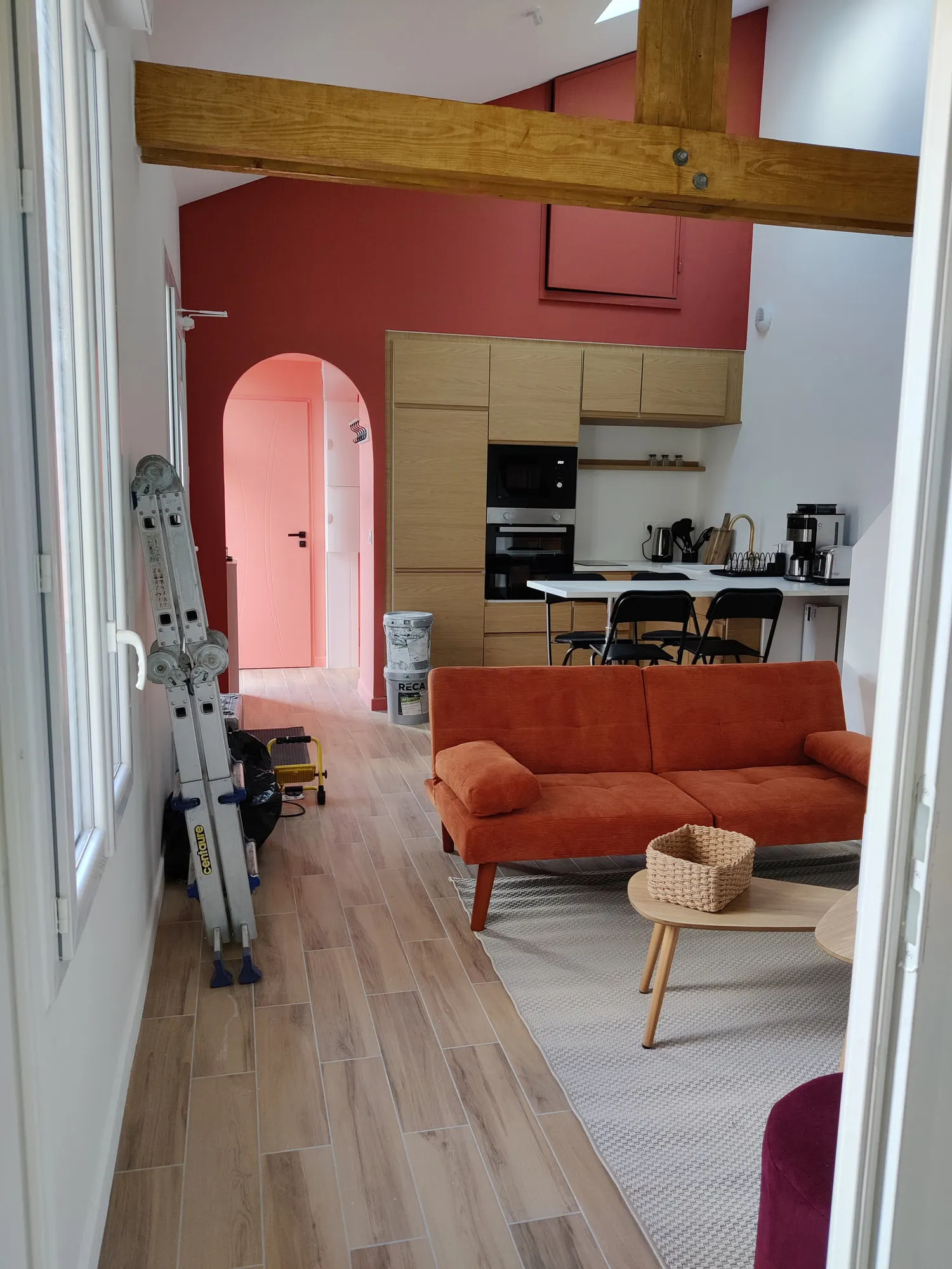Séjour livré avec mur terracotta, poutres apparentes et canapé